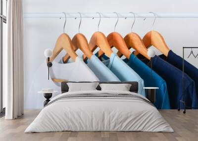 close up collection shade of blue tone color t-shirts hanging on wooden clothes hanger in closet or clothing rack over white background Wall mural