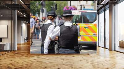 London, England, UK; 13th July 2018; Rear view of Two Female Metropolitan Police Officers in the Street.  Unfoccused Police Van Behind Wall mural