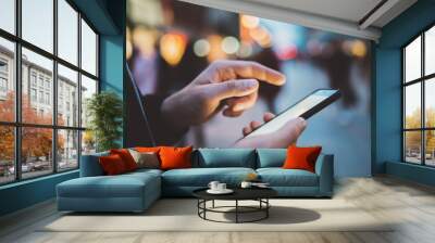 Closeup of male hands typing an sms message via smartphone outside, hipster man enjoying evening walk and using his cellphone, bokeh lights Wall mural