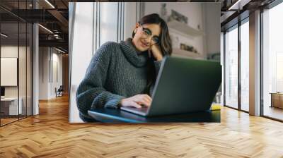 Happy young woman sitting at home in earphones using laptop computer having chat online with friends via app, businesswoman working at home having online meeting in video call with colleagues Wall mural