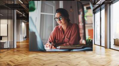 Pretty young woman an advertising copywriter in eyeglasses working at home using laptop, female graphic designer working in modern studio, Networking Freelancer Businesswoman Designer Entrepreneur Wall mural