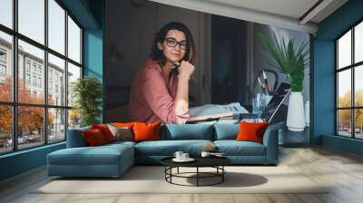 Pretty young woman an advertising copywriter in eyeglasses working at home using laptop, female graphic designer working in modern studio, Networking Freelancer Businesswoman Designer Entrepreneur Wall mural