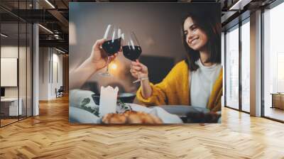 Romantic dinner, beautiful young couple having dinner drinking red wine in restaurant, best friends making cheers with glasses of wine enjoying homemade food, sweet couple dining by candlelight Wall mural