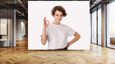 Pretty smiling woman in a white shirt and eyeglasses showing OK sign to express appreciation Wall mural