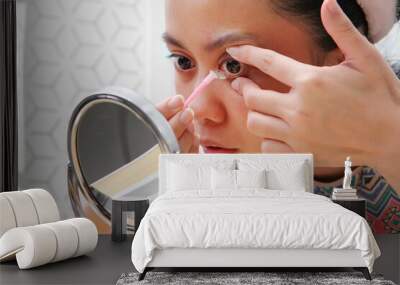 Young indonesian woman putting contact lens in her eye. Health And Eyes Care Concept. Wall mural