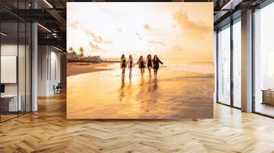 a group of Asian teenagers in shirts running with their friends with very cheerful expressions on the beach Wall mural