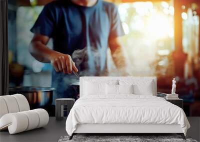 A man in a casual shirt is seen stirring a pot in a bright kitchen, with steam rising and flames visible Wall mural