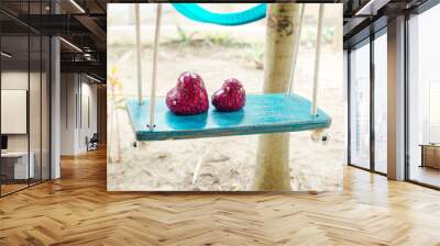 Close up of two red hearts on wooden table swing. Wall mural