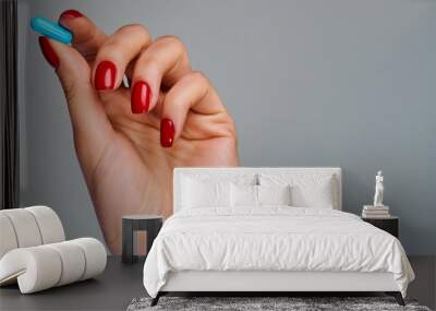 Female hand with red nails holds a blue pill in fingers. Medical concept Wall mural