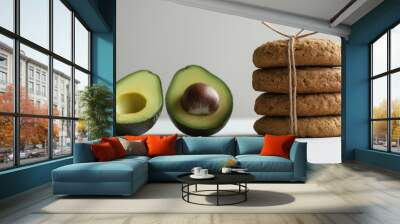 avocado as a butter alternative: a clean, minimalist photograph of a stack of rustic cookies tied with simple twine on the right side, accompanied by a whole avocado and a half-cut avocado on the left Wall mural