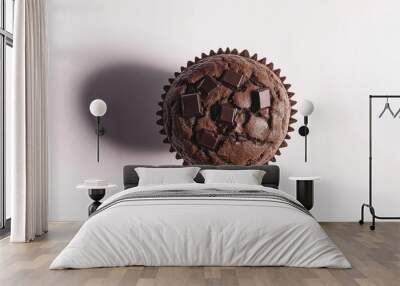 a chocolate muffin with a cracked top and chocolate chunks against an isolated white background Wall mural