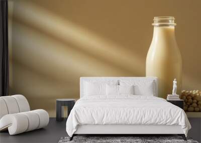 a glass bottle of soy milk with soybeans scattered around against an isolated soft brown background Wall mural