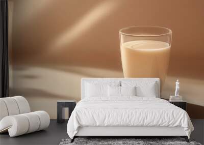 a glass of almond milk with a few almonds beside it against an isolated soft apricot background Wall mural