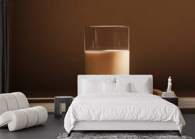 a glass of almond milk with a few almonds beside it against an isolated soft brown background Wall mural