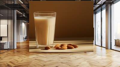 a glass of almond milk with a few almonds beside it against an isolated soft brown background Wall mural