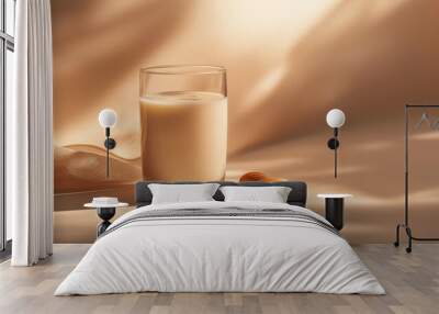 a glass of almond milk with a few almonds beside it against an isolated soft cinnamon background Wall mural