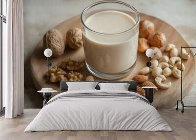 a high-angle shot of a glass of soy milk placed next to a variety of nuts such as almonds, cashews, and walnuts on a wooden board Wall mural