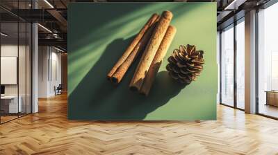 two cinnamon sticks and a small pine cone arranged artistically against an isolatedmuted olive greenbackground Wall mural