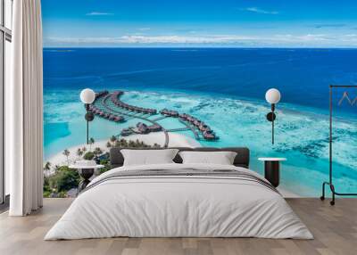 Aerial view of Maldives island, luxury travel water villas resort and wooden pier. Beautiful sky and ocean lagoon beach background. Summer vacation holiday. Paradise aerial landscape panorama Wall mural