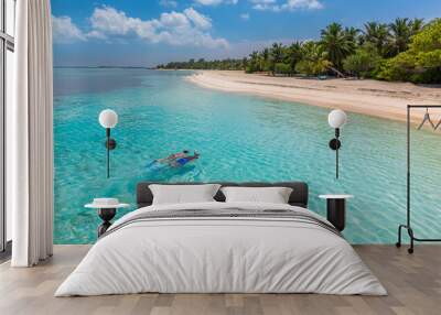 Caucasian couple of tourists snorkel in crystal turquoise water near Maldives Island. Recreational outdoor sport at luxury resort beach scene, calm sea water, couple exotic water, underwater wildlife Wall mural