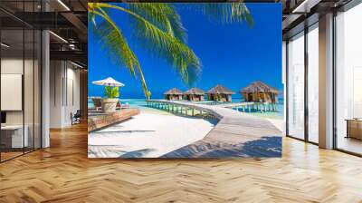 Luxury hotel with water villas and palm tree leaves over white sand, close to blue sea, seascape. Beach chairs, beds with white umbrellas. Summer vacation and holiday, beach resort on tropical island Wall mural