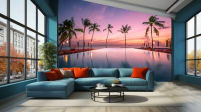 Luxury sunset over infinity pool in a summer beachfront hotel resort at tropical landscape. Tranquil beach holiday vacation background mood. Amazing island sunset beach view, palms swimming pool Wall mural