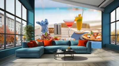 Pizza and tropical cocktail with beautiful sunny vacation infinity swimming pool ocean view. Beach restaurant, sea view, glasses, plates, food, tropical cocktail, blur loungers, chairs, sun umbrellas
 Wall mural