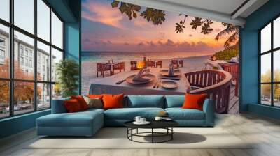 Romantic sunset on tropical island shore. Dinner table in beach restaurant. Beautiful sunset sky, tables chairs in sand, close to sea, horizon. Romance, couple honeymoon, wedding destination, vacation Wall mural