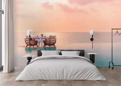 Summer love and romance table set-up for a romantic dinner meal with infinity pool reflection chairs under sunset sky and sea in the background. Luxury destination dining, romantic dinner for couples Wall mural