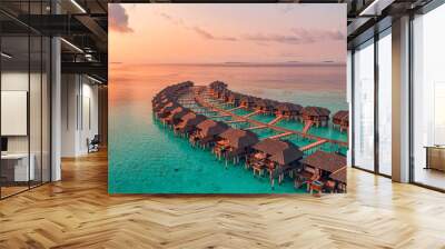 Sunset on Maldives island, luxury water villas resort and wooden pier. Beautiful aerial sky clouds and beach background. Summer coast vacation travel. Paradise sunrise landscape. Pristine sea bay Wall mural