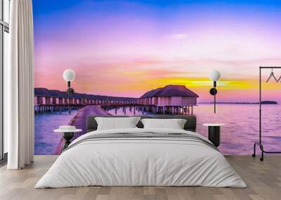 Sunset on Maldives island, luxury water villas resort and wooden pier. Beautiful sky and clouds and beach background for summer vacation holiday and travel concept Wall mural