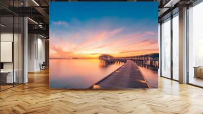 Sunset on Maldives island, luxury water villas resort and wooden pier. Beautiful sky and clouds and beach background for summer vacation holiday and travel concept Wall mural