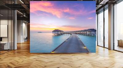 Sunset on Maldives island, luxury water villas resort and wooden pier. Beautiful sky and clouds and beach background for summer vacation holiday and travel concept Wall mural