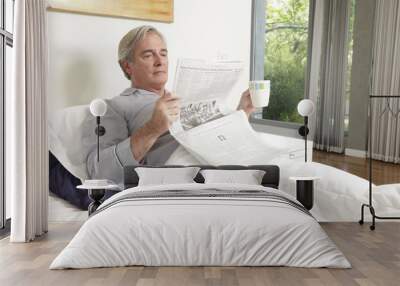 Senior man drinking coffee and reading newspaper Wall mural