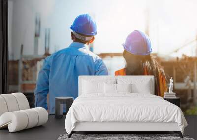 Asian man civil engineer and woman architect wearing blue safety helmet meeting at contruction site. Wall mural