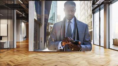 Handsome professional male walking in the city using his phone Wall mural