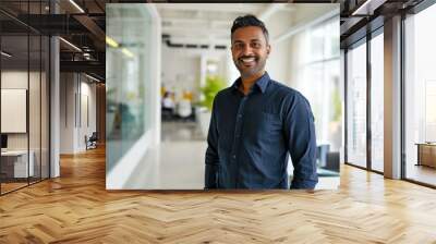 a happy and confident young Indian business man standing in the office, smiling professional manager and executive, exudes cheer while reflecting on financial success Wall mural