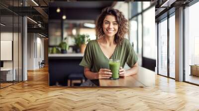 beautiful smiling girl with a green smoothie cocktail sitting at a table in a cafe, healthy eating and diet Wall mural