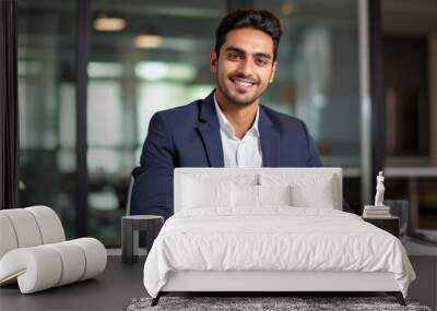 happy young Indian businessman employee manager using a tablet computer, looking at the camera at his office desk Wall mural