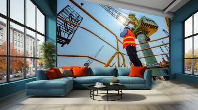 stevedore or foreman, engineering, loading master talks to crane driver by walkie talkie for safety lifting  the goods or shipment, lifting by gantry crane, working at risk on the high level insurance Wall mural