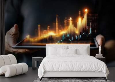 A man's hands hold a tablet with a glowing financial chart. Wall mural