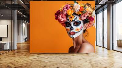 Beautiful woman dressed for Halloween on orange background. Young hispanic woman wearing flowers in her head, with painted skull on her face for Mexico's Day of the Dead  Wall mural