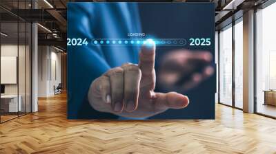 A businessman touches a digital progress bar indicating the transition from 2024 to 2025, symbolizing strategic planning, future readiness and challenge strategy for business startup Wall mural