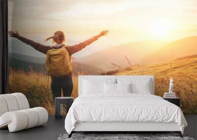 A woman is standing in a field of tall grass, with her arms outstretched Wall mural