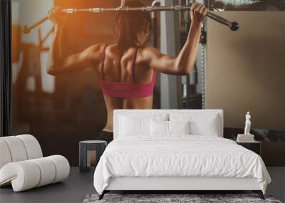 Brutal athletic woman pumping up muscles with dumbbells Wall mural