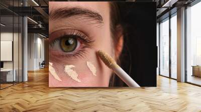 Close-Up Shot Of A Girl Applying Concealer Under Her Eyes And Makeup Foundation On Her Eyelids Wall mural