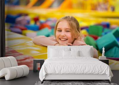 Pretty girl kid sitting in colorful cube trampoline at playground park and smiling. Beautiful female child happy during active entertaiments indoor Wall mural