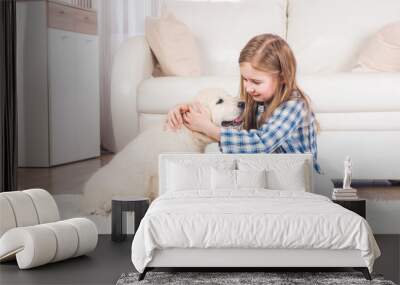 Smiling little girl sitting with fluffy retriever puppy at home Wall mural