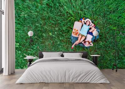 two little girls have a picnic with pizza and lying on a green grass, aerial top view Wall mural