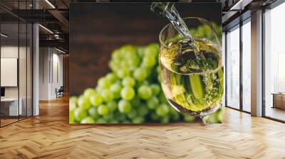 Pouring white wine into a glass with a bunch of green grapes against wooden background Wall mural